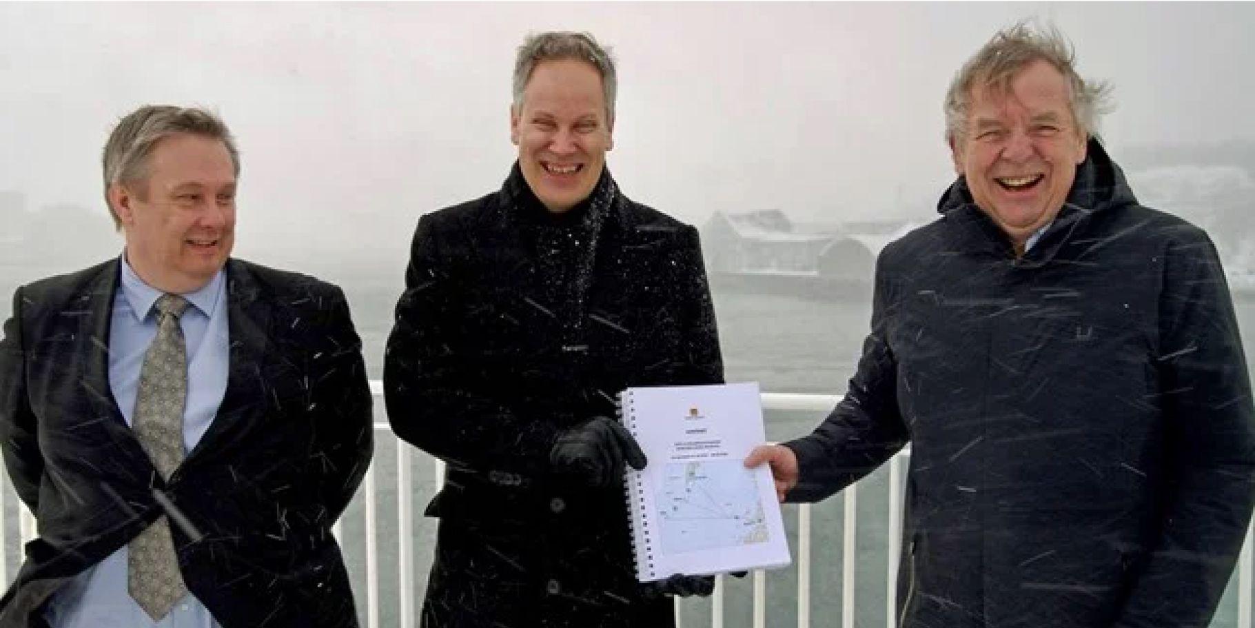 Smilende ledelse i Torghatten og Statens Vegvesen, med kontrakt på papir i hånden. Det blåser og snør.